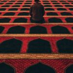 man in red shirt kneeling on red and black carpeted floor